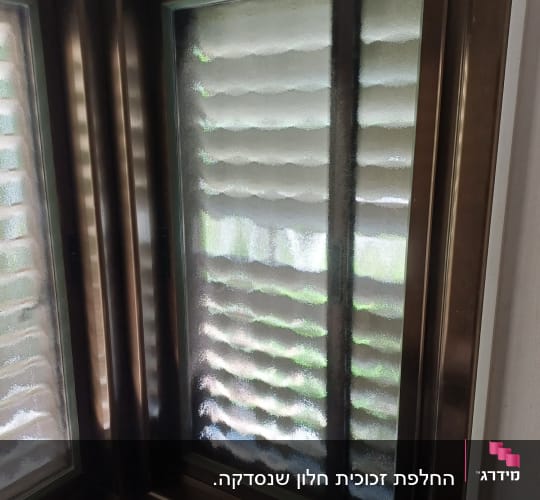 חלון זכוכית עם מסגרת מתכת בפינת חדר
